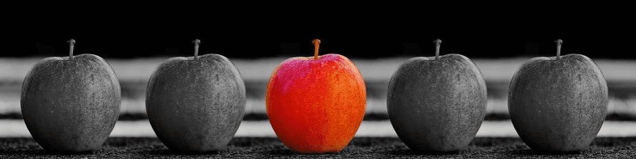 a red apple among 4 black and white apples